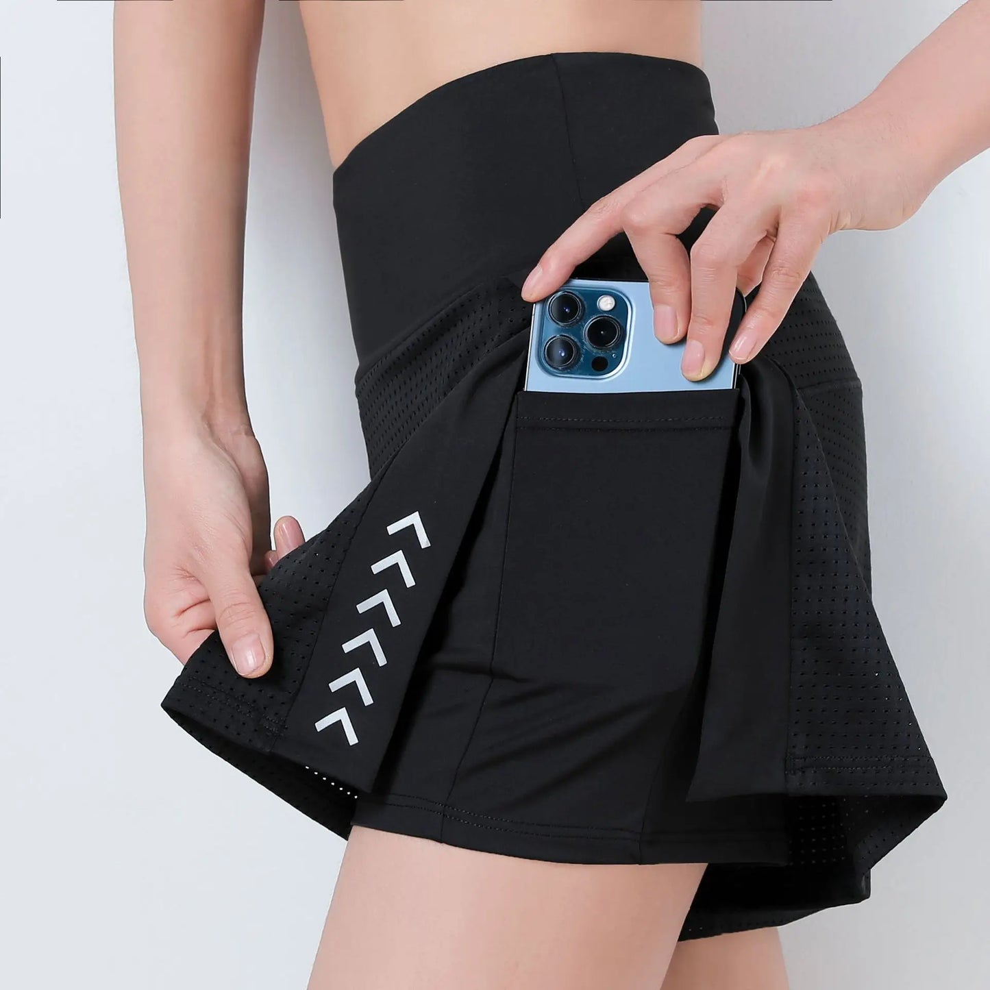 Person wearing black athletic shorts with a phone pocket, holding a blue phone.