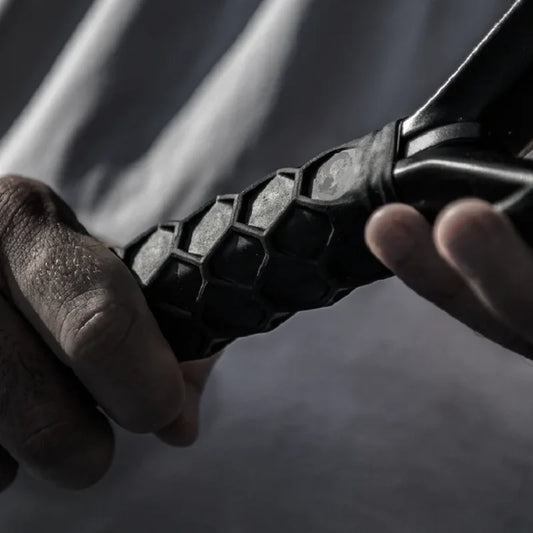 Close-up of a hand holding a black honeycomb-patterned object against a blurred background