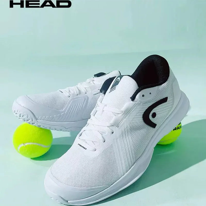 White tennis shoes with black accents and a tennis ball on a light green background, featuring the HEAD brand.