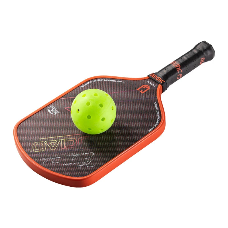 Orange and black pickleball paddle with a green ball on a white background