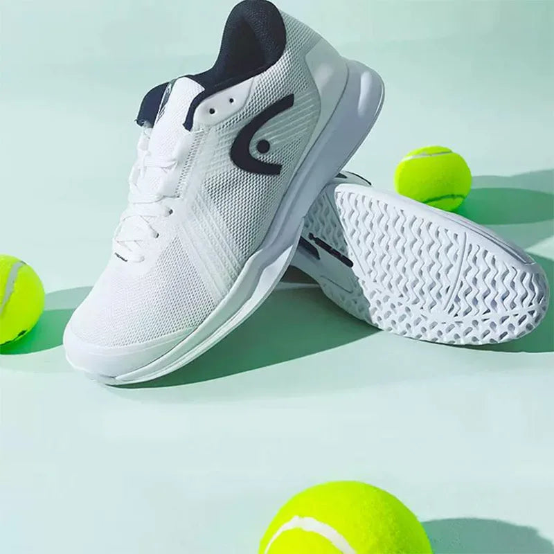 White tennis shoes with black accents on a light green background with tennis balls.