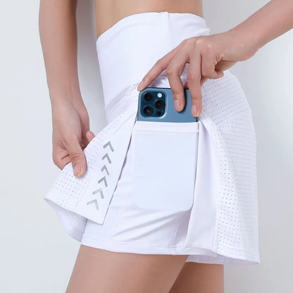 Person wearing a white athletic skirt holding a phone and a small pouch on a plain background